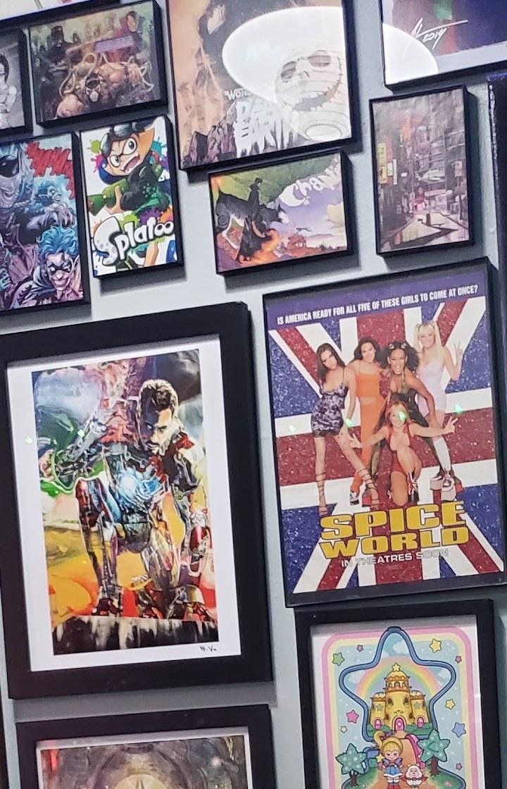 A wall of framed prints and comic art beside the bar at Club Geek.
