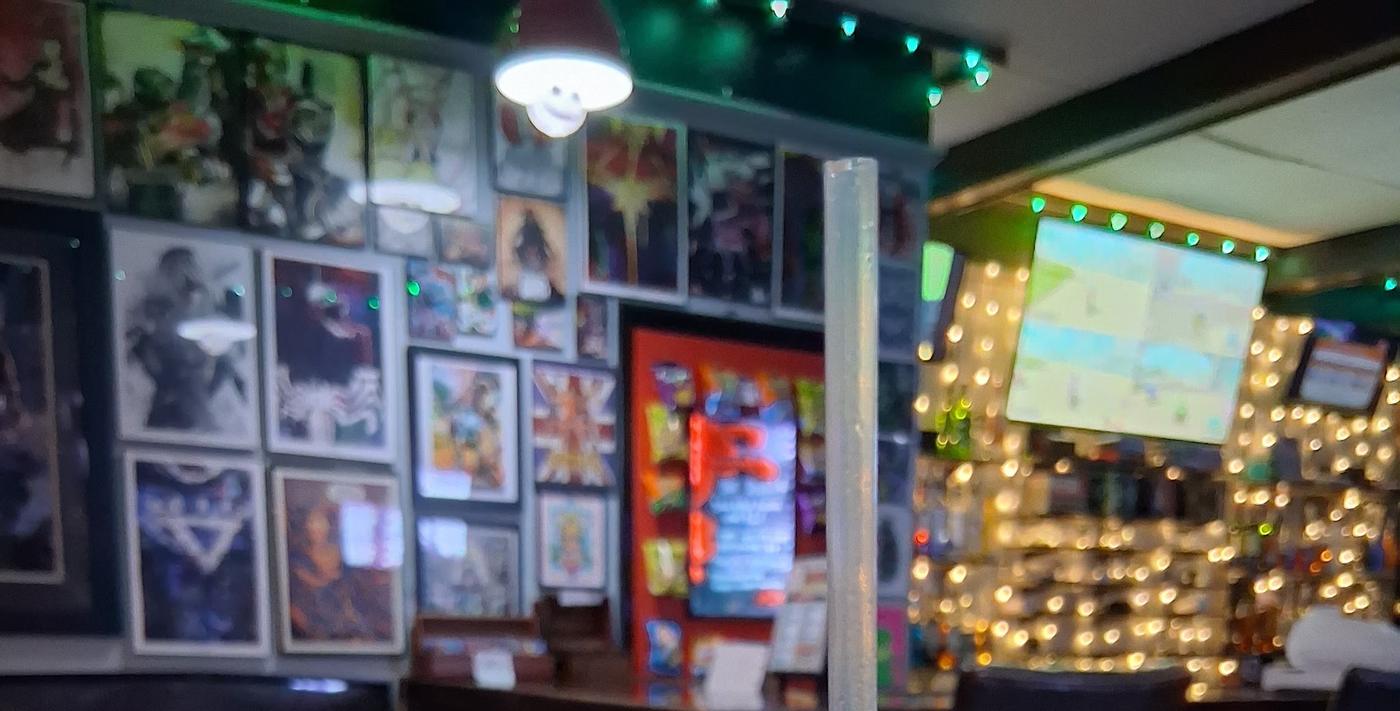 The room at Club Geek: framed art across the wall, string lights and the lit back bar.